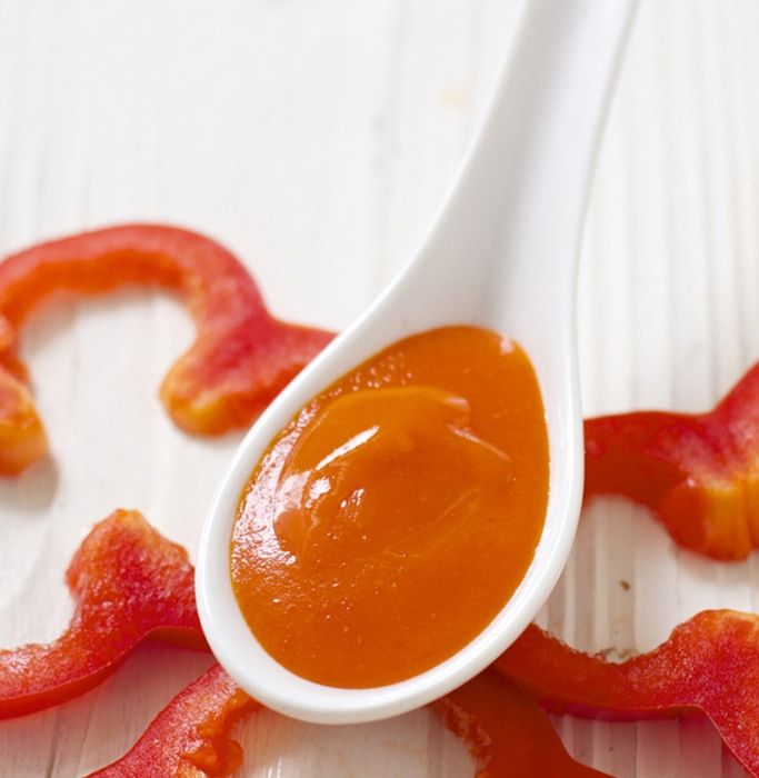 a spoon full of sauce sitting on top of bacon