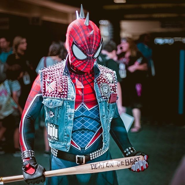 a man dressed as spider - man holding a baseball bat