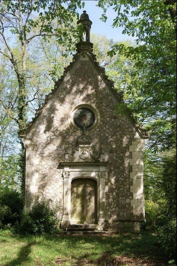 an old stone building with a clock on it's side in the middle of some trees