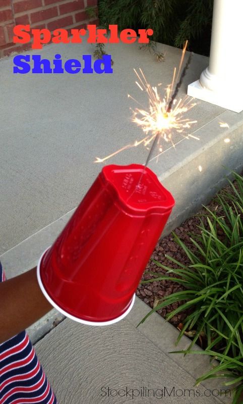 a person holding a red fire hydrant with sparkler in it's mouth