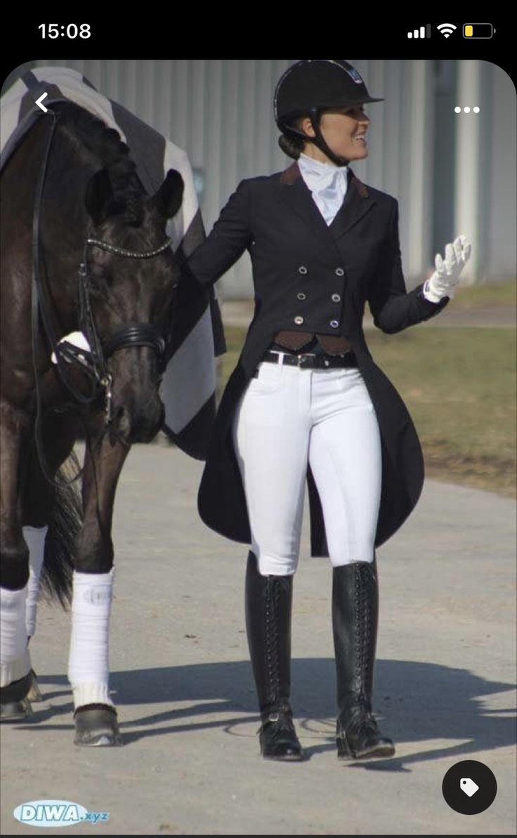 a woman in riding gear standing next to a horse