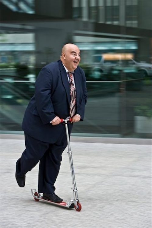 a man in a suit riding on a scooter