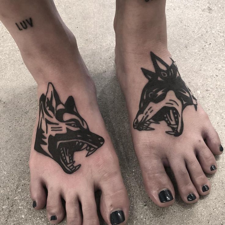 two black and white tattoos on the feet of a person with one foot in the shape of a wolf