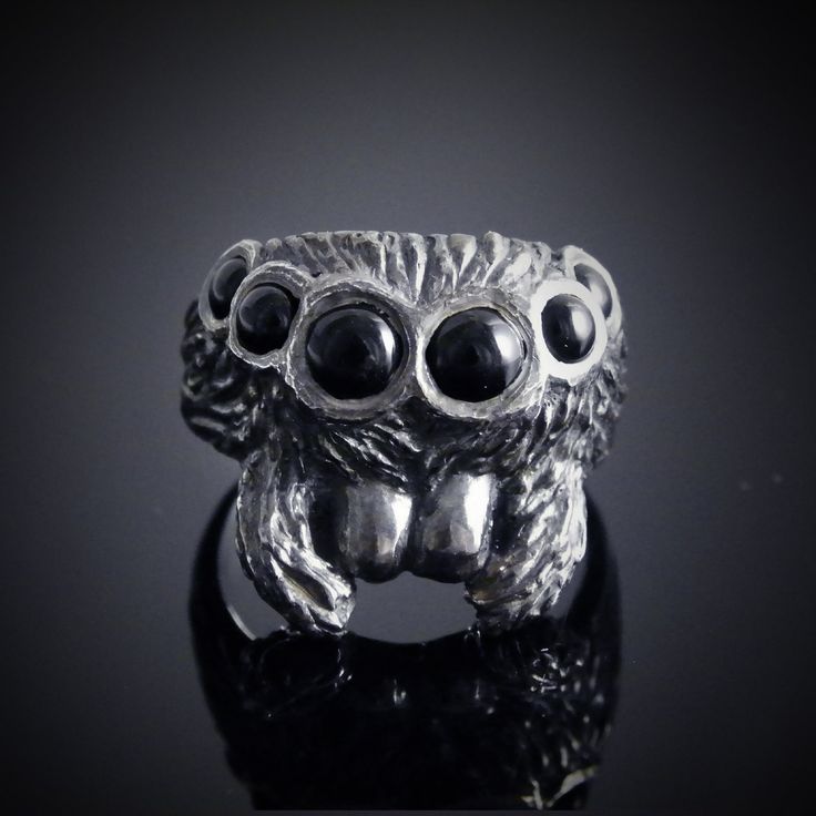 a silver ring with three black stones on it's face and two eyes in the middle