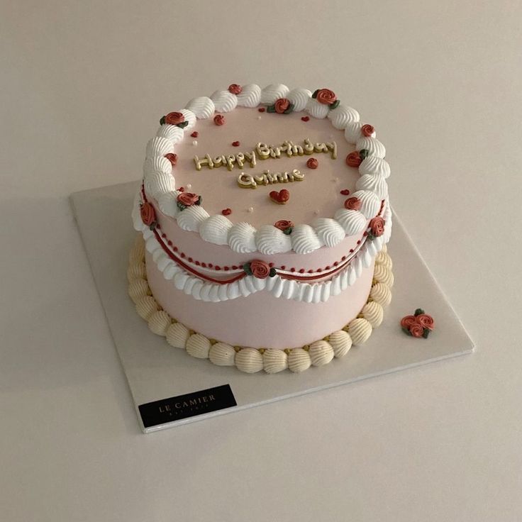 a birthday cake with white frosting and red decorations