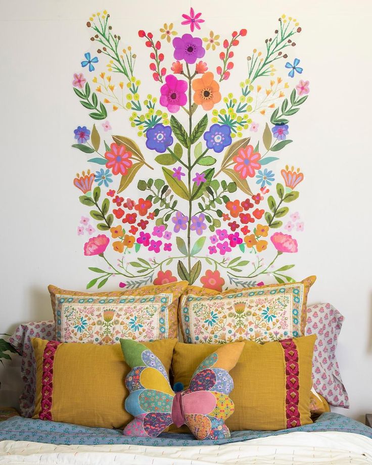 a bed topped with pillows next to a colorful painting on the side of a wall