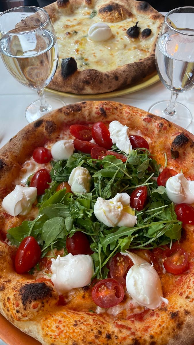 a pizza with tomatoes, mozzarella and spinach on it sitting on a table