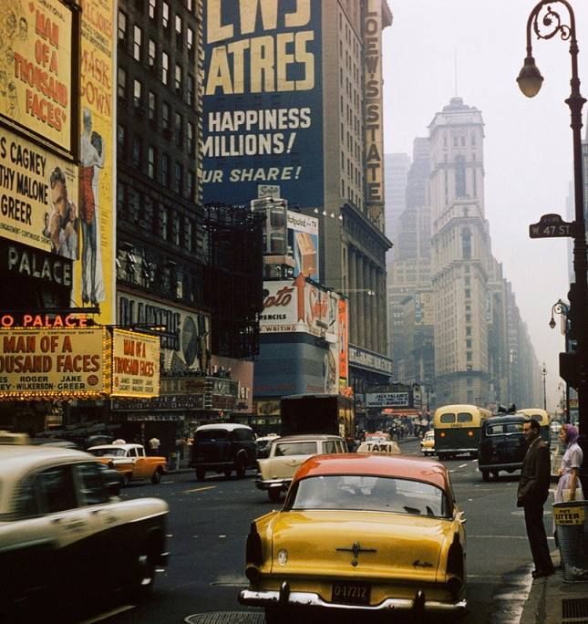 a busy city street filled with lots of traffic and people walking on the side of it