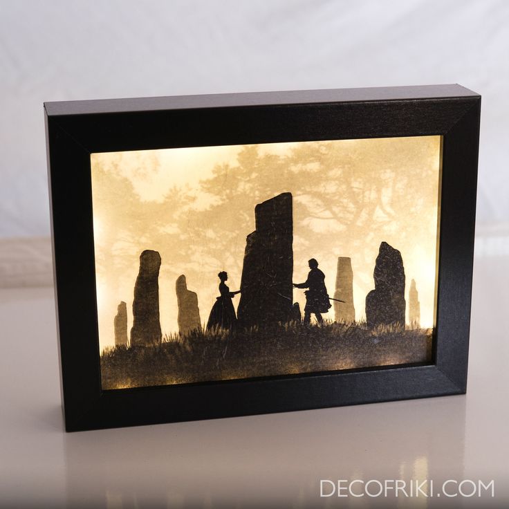 a shadow box with an image of people standing in front of the tombstones at night