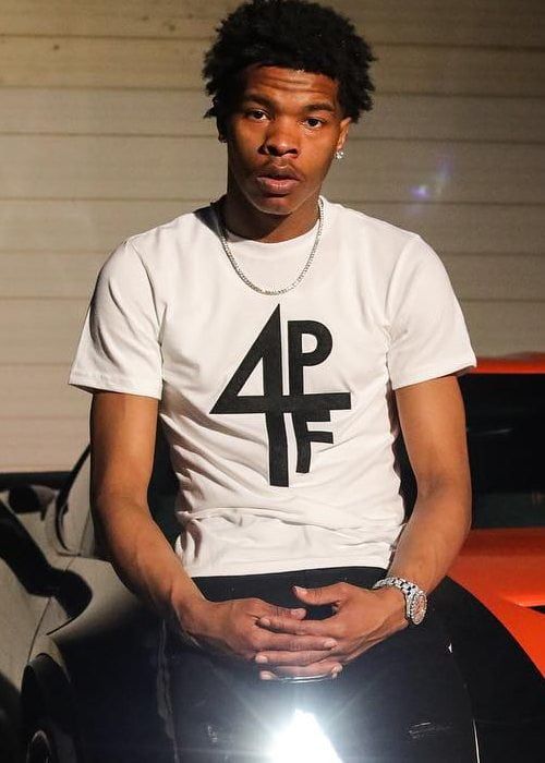 a young man sitting on top of a car in front of a building with a bright light