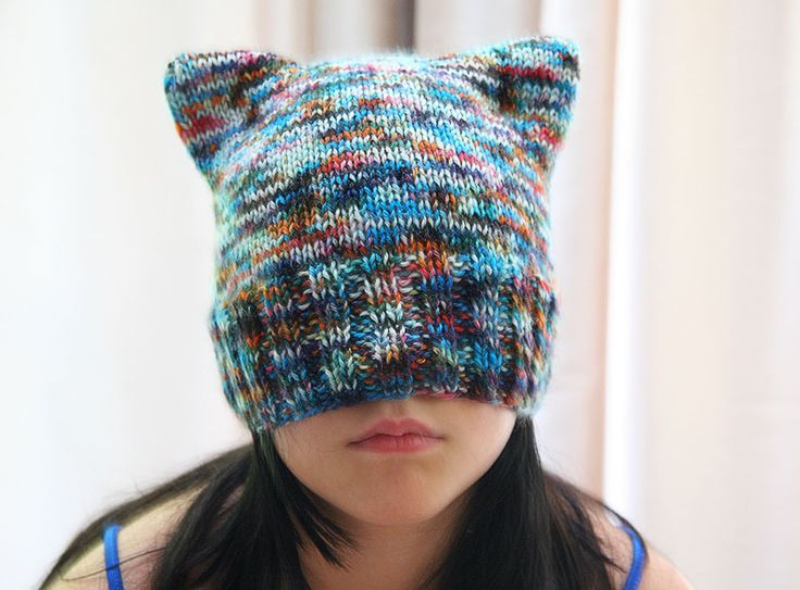 a woman wearing a knitted hat with cat ears on it's head and looking at the camera