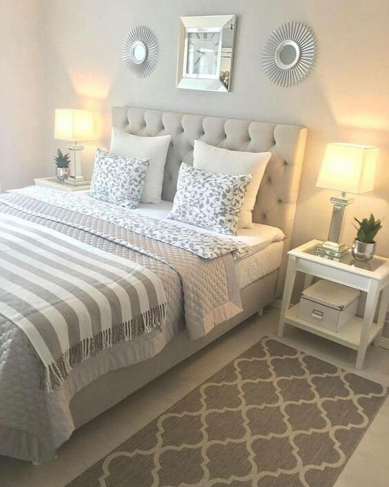 a bedroom with a bed, nightstands and two lamps on either side of the bed