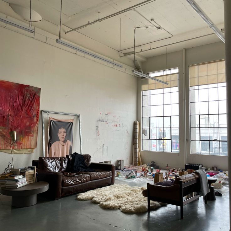 a living room filled with lots of furniture and paintings hanging on the wall above it