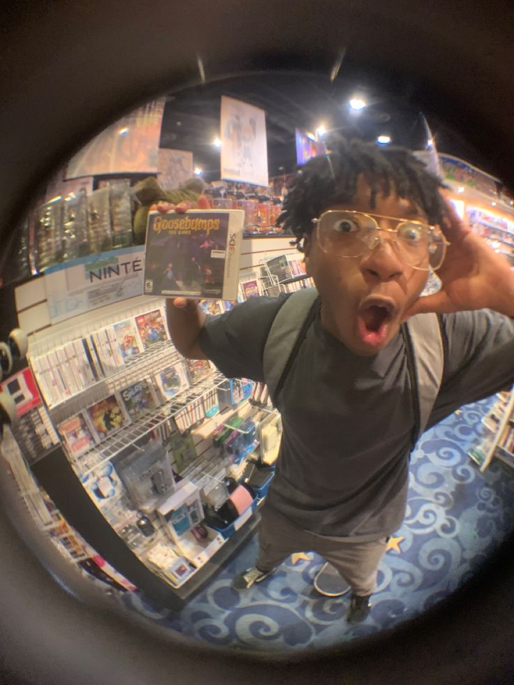 a man with glasses making a funny face while standing in front of a magazine display