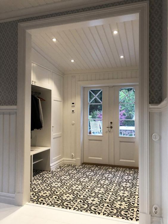 an open door leading into a white room with black and white floor tiles on the floor