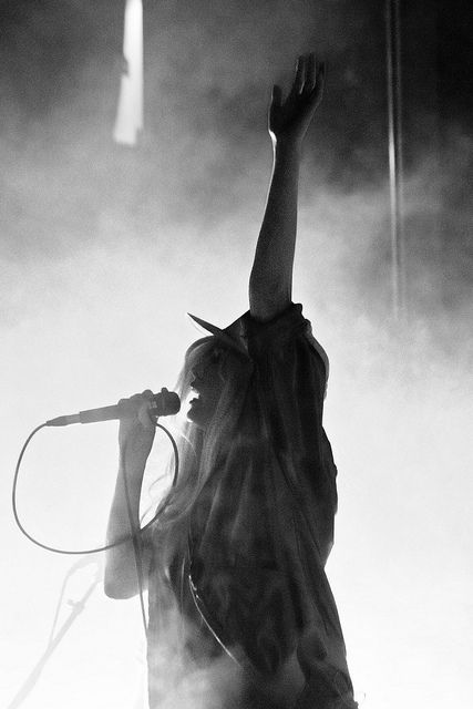 a woman standing on top of a stage with her arms up in the air while holding a microphone