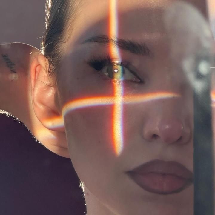 a woman looking through a mirror with the reflection of her face and cross on it