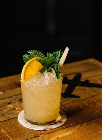 a glass filled with ice and lemon on top of a wooden table