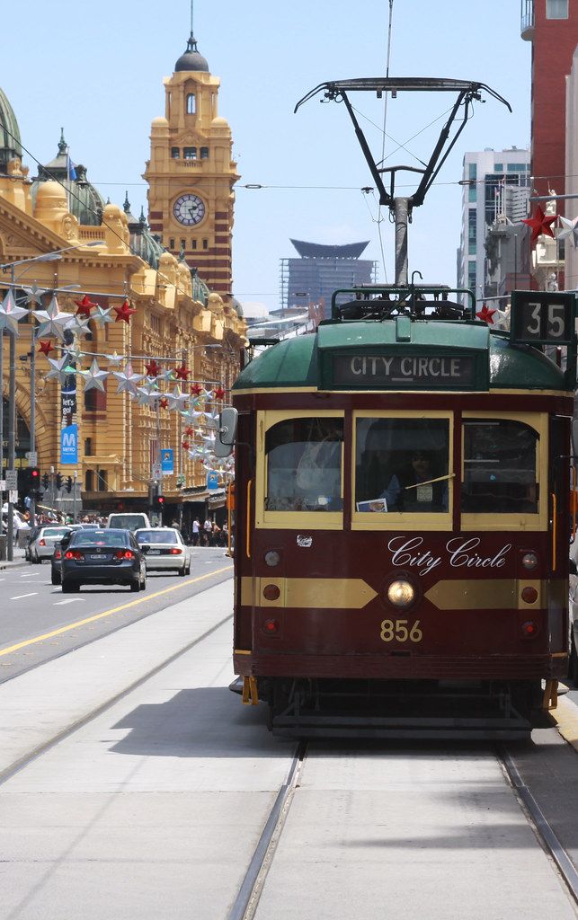 a trolley car is traveling down the street in front of some tall buildings and cars