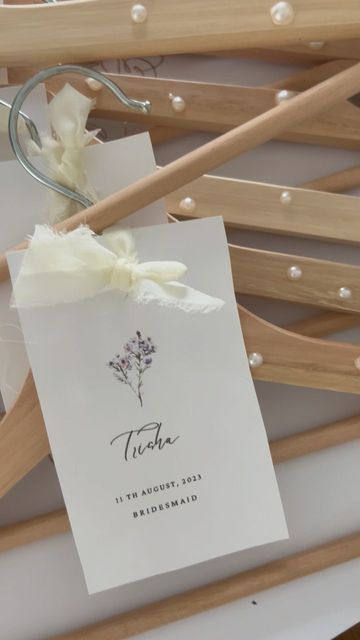 there is a card with a flower on it next to some wooden clothes hangers