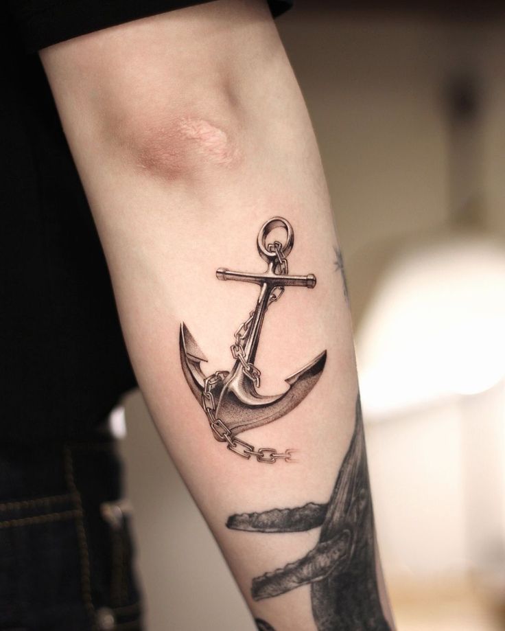 a person with a tattoo on their arm holding an anchor