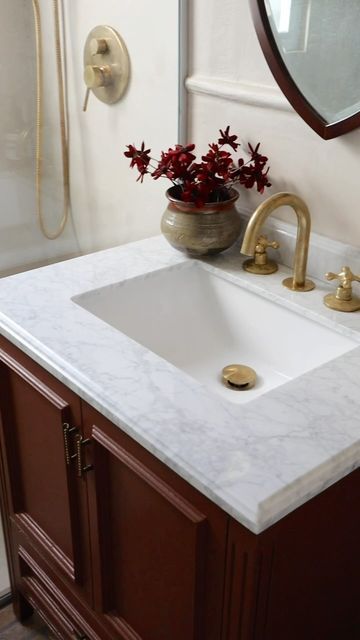 a white sink sitting under a bathroom mirror next to a shower head mounted faucet