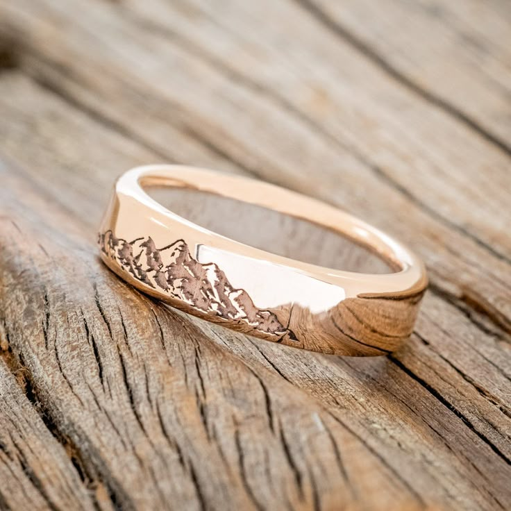 a gold ring with mountains engraved on it