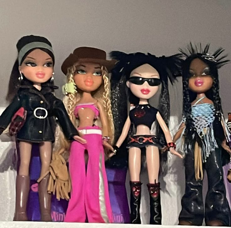 five dolls are lined up on the shelf together, all wearing clothes and hats with fringes