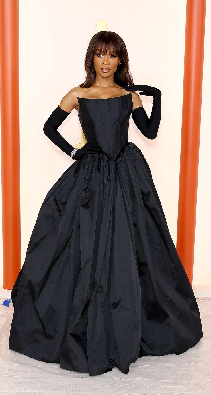 a woman in a black gown posing for the camera with her hands on her hips