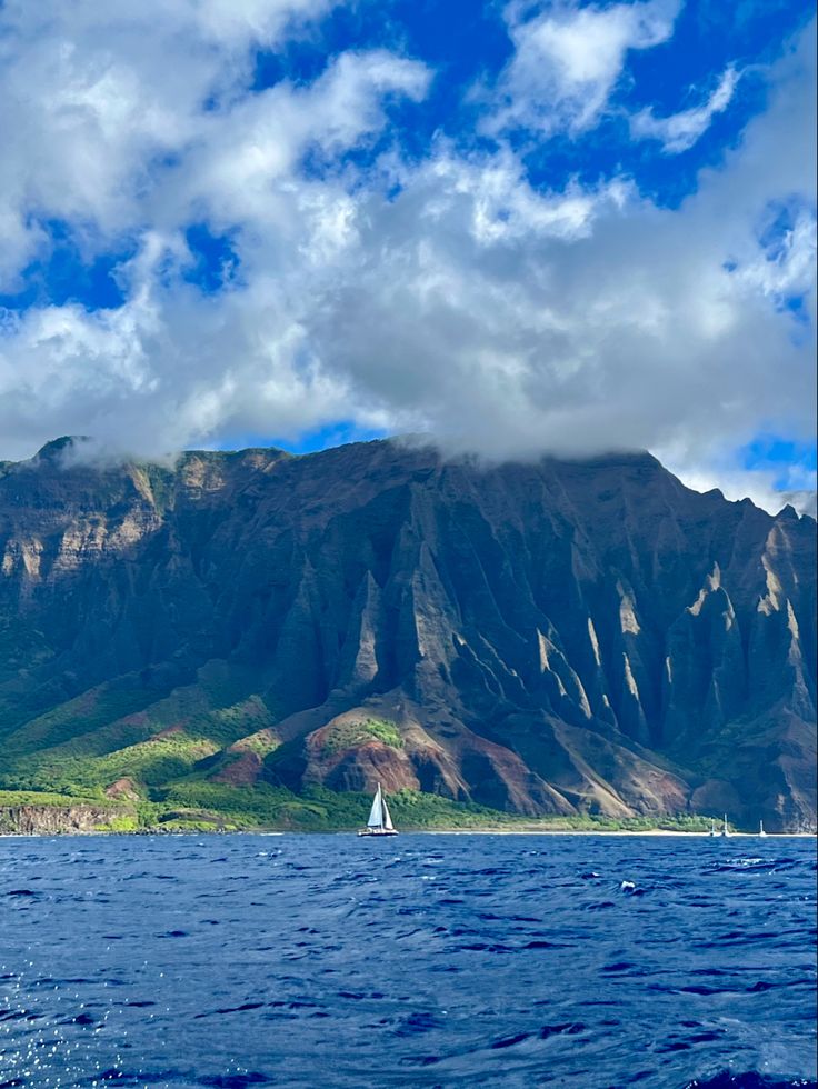 a sailboat in the ocean near a mountain