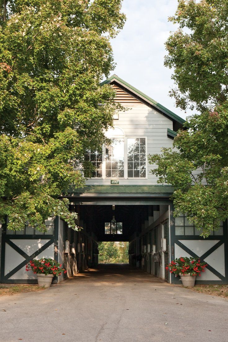 the entrance to a large white barn surrounded by trees