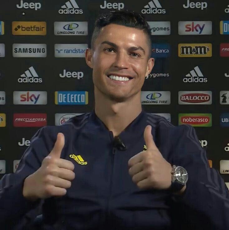 a man giving the thumbs up sign in front of a wall