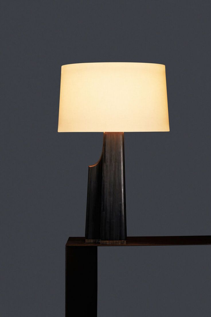 a table lamp with a white shade on it's side and a black base