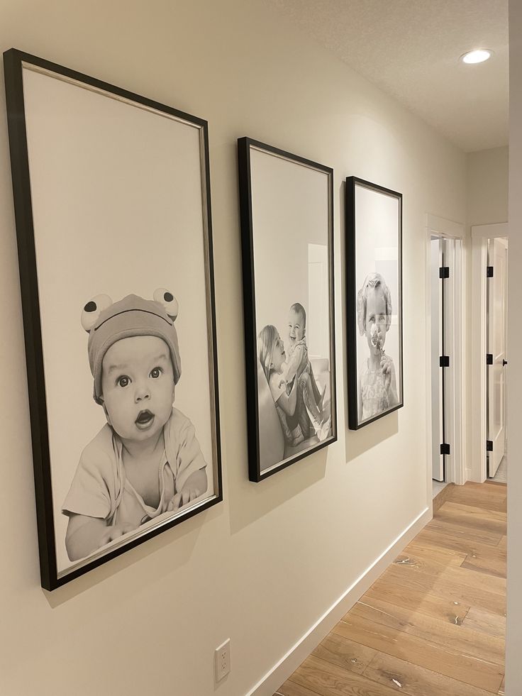 three black and white pictures hang on the wall next to a hallway with hardwood floors