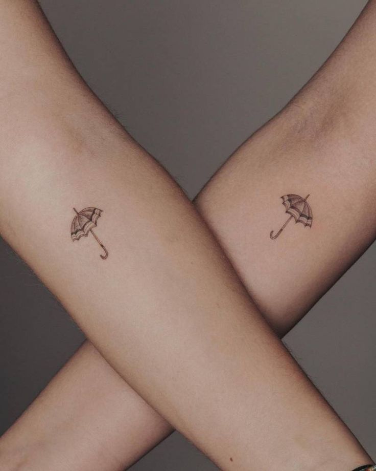 two people with matching umbrella tattoos on their arms