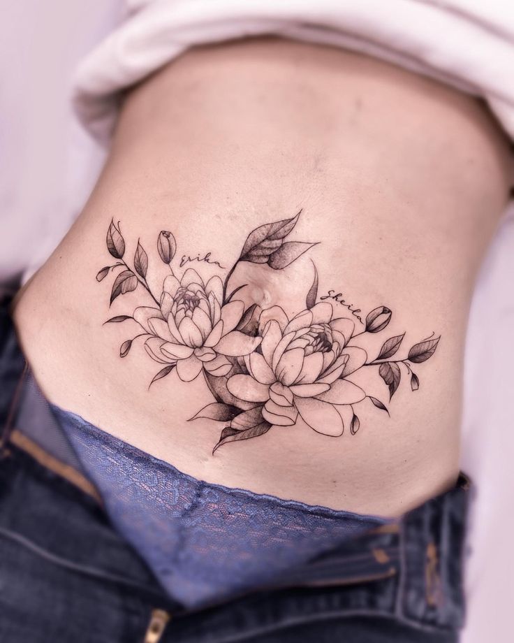 a woman's lower back tattoo with flowers on her stomach and leaves growing out of it