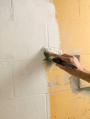 a man is using a paint roller to paint the wall with yellow and white colors