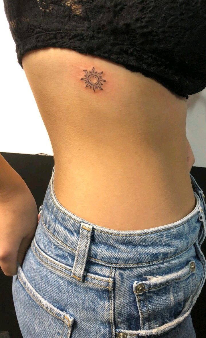 a woman's stomach with a small sun tattoo on her lower back and side