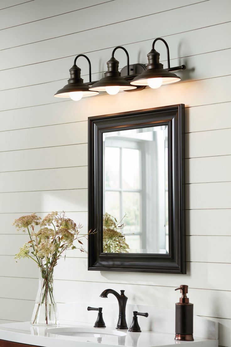 a bathroom vanity with two lights above it and a mirror on the wall behind it