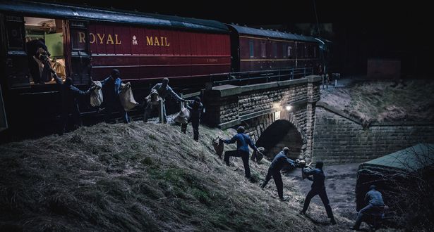 several people are walking up the side of a train track at night, with one person holding onto another man's hand