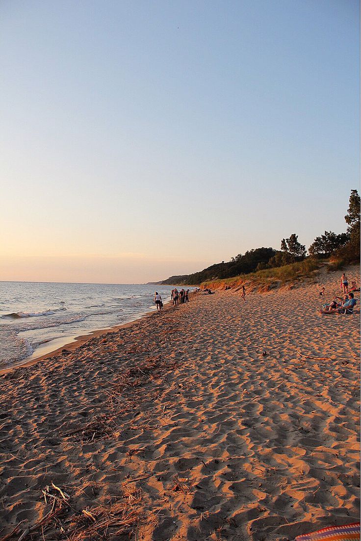 people are on the beach at sunset