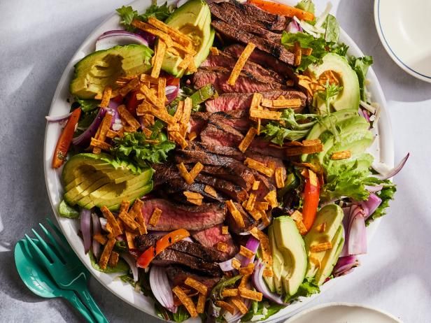 a steak salad with lettuce, carrots, onions and avocado