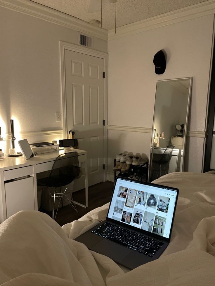 an open laptop computer sitting on top of a bed in a room with white walls