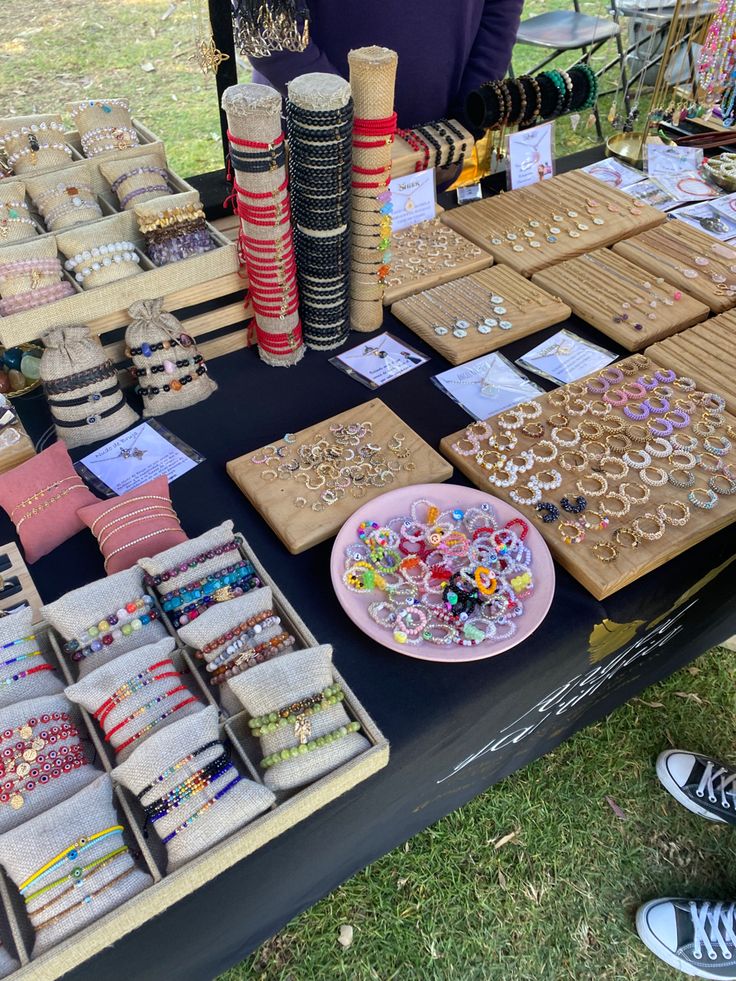 a table topped with lots of different types of bracelets and necklaces on display