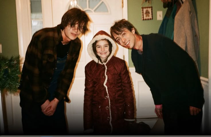 three young men standing next to each other in front of a door