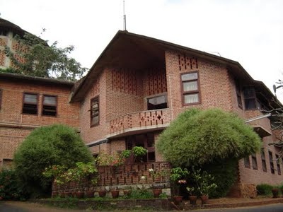 a large brick building with lots of windows and bushes on the side of the street