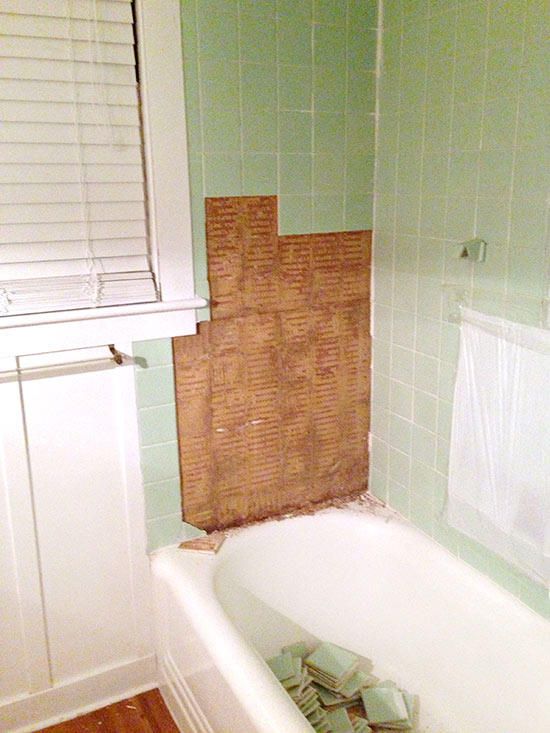 a bathroom with green walls and white fixtures, including a bathtub in the corner