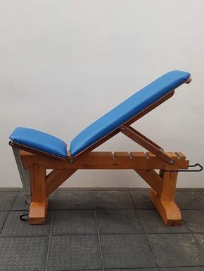 a wooden bench sitting on top of a tile floor next to a wall with a blue cushion