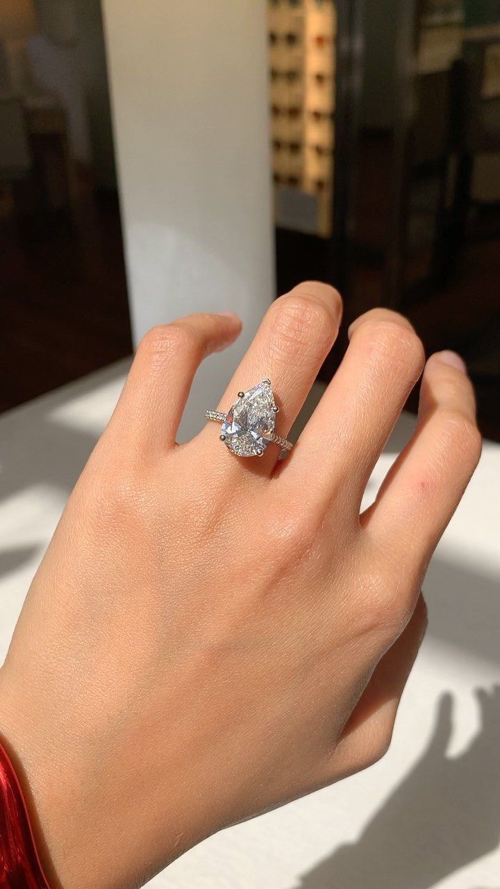 a woman's hand with a diamond ring on top of her left hand,