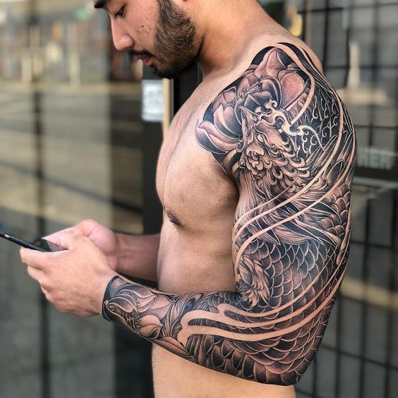 a man with a dragon tattoo on his arm holding a cell phone